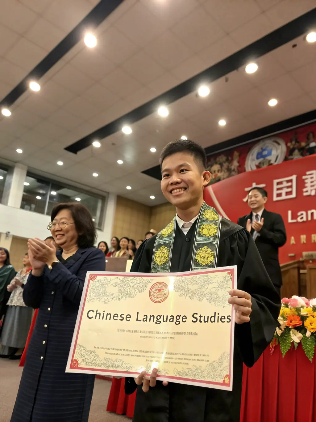 A photo of a smiling student receiving a scholarship certificate from a representative of Ex Mays Global Charity. The student is standing in front of a school banner.
